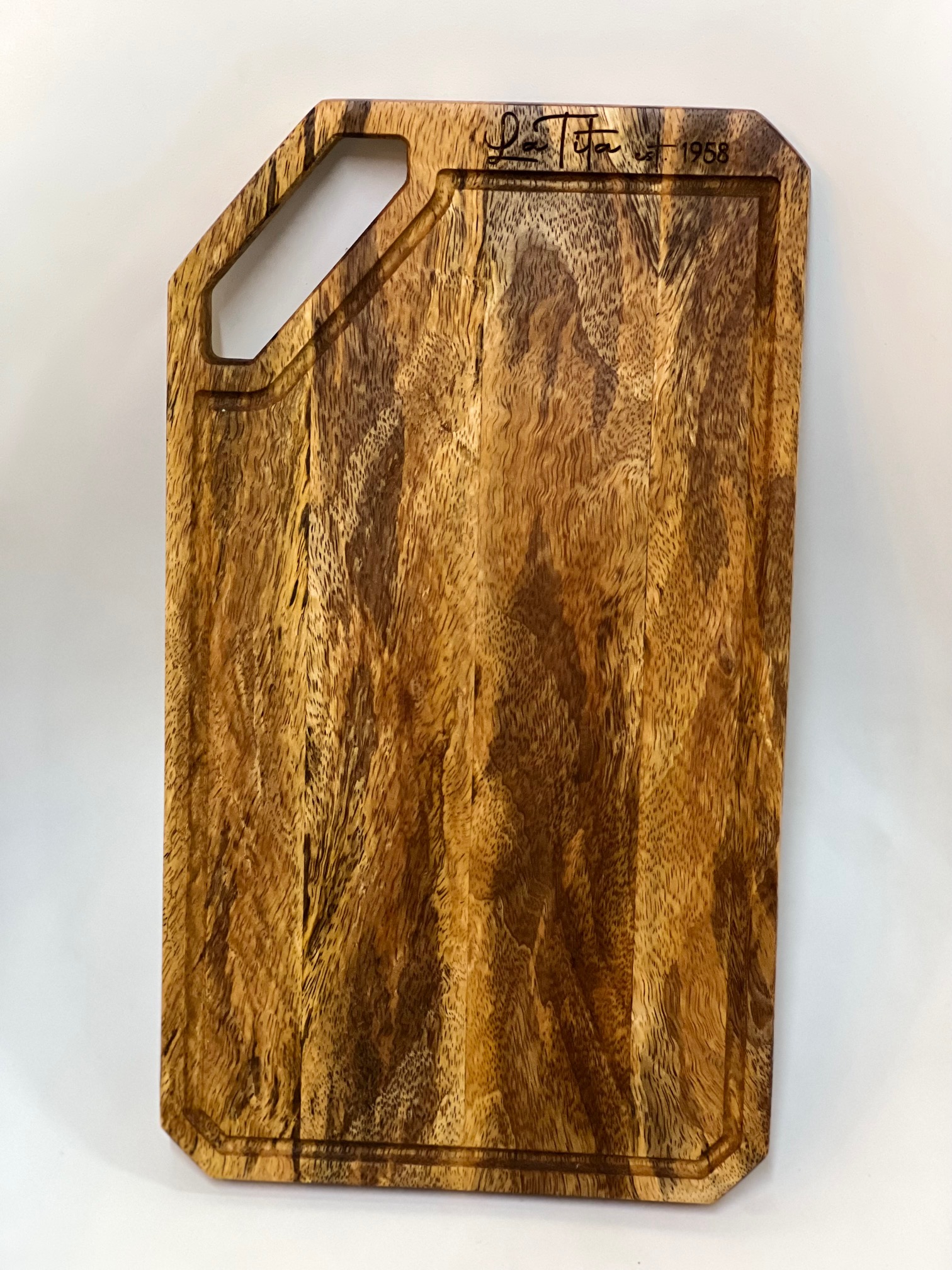 Tabla de madera grabada con el texto 'La Tita, est. 1958' en letra cursiva.